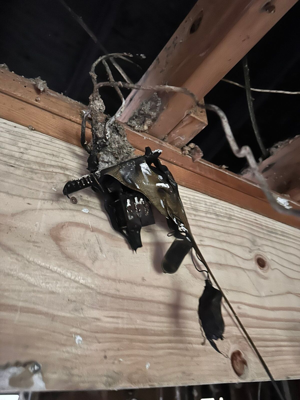 Fire-damaged electrical wiring and charred framing exposed during an inspection